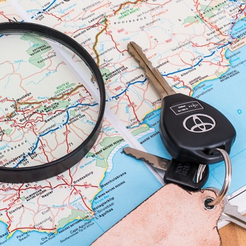 Fahren im Ausland mit Landkarte und Autoschlüssel dargestellt.